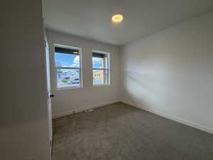 Carpeted spare room featuring baseboards