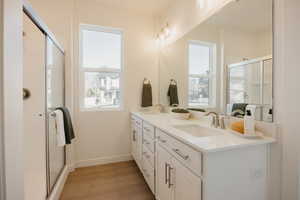 Full bathroom featuring double vanity, a shower stall, and light wood-style flooring