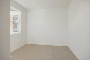 Spare room featuring light carpet and baseboards
