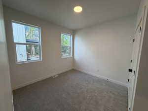 Unfurnished room featuring dark carpet and baseboards