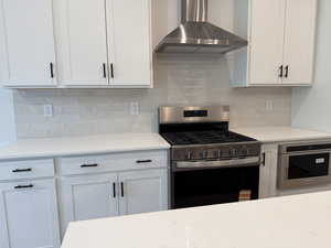 Kitchen featuring stainless steel appliances, white cabinetry, tasteful backsplash, and light stone counters