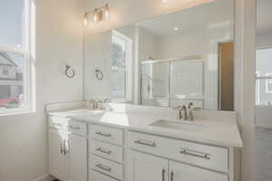 Full bathroom with double vanity and a shower stall