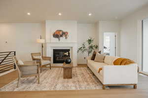 Living area with light wood-type flooring, recessed lighting, and a tiled fireplace