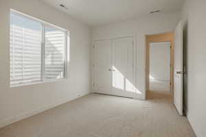 Unfurnished bedroom with light colored carpet and a closet