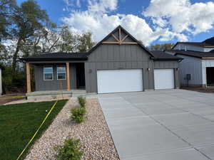 View of front facade featuring board and batten siding, a garage, a porch, and concrete driveway