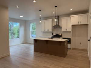 Dual tone kitchen with decorative light fixtures, two tone color scheme, an island with sink, a breakfast bar, and tasteful backsplash