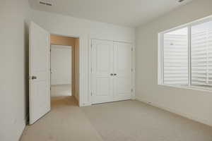 Unfurnished bedroom with light carpet and a closet