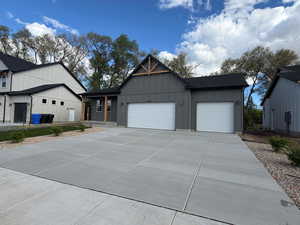 View of front facade with a garage, board and batten siding, concrete driveway, and roof with shingles