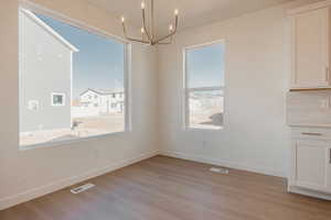 Unfurnished dining area featuring light wood-style flooring and hanging lights