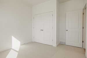 Unfurnished bedroom with light colored carpet and baseboards