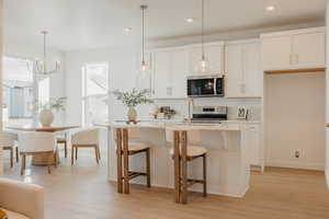 Kitchen featuring light wood-type flooring, a kitchen breakfast bar, and white cabinetry