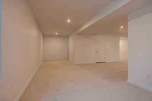 Finished below grade area with light colored carpet and recessed lighting