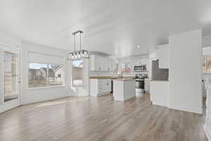Kitchen with a kitchen island, white cabinetry, open floor plan, and hanging light fixtures