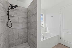 Bathroom featuring a stall shower, a garden tub, and wood finished floors
