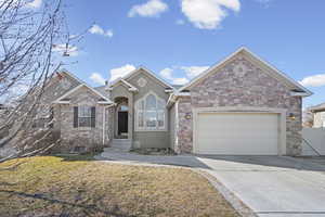 Ranch-style house featuring an attached garage, driveway, stucco siding, and stone siding