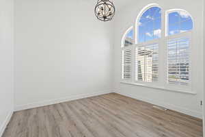 Spare room with light wood-style flooring and a chandelier