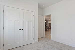Unfurnished bedroom with light colored carpet and a closet