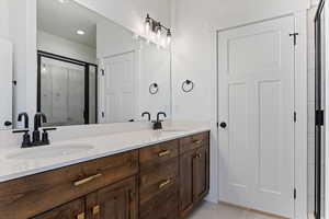Full bath with double vanity, a stall shower, and light tile patterned floors