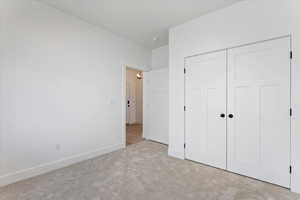 Unfurnished bedroom with a closet and light colored carpet