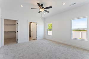 Unfurnished bedroom featuring a walk in closet, light carpet, recessed lighting, and ceiling fan