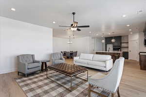 Living room with light wood-style flooring, recessed lighting, and ceiling fan