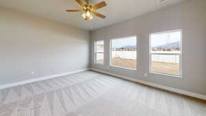 Empty room with carpet, a ceiling fan, and a mountain view