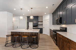 Kitchen featuring stainless steel appliances, tasteful backsplash, a breakfast bar, open shelves, and light wood-type flooring