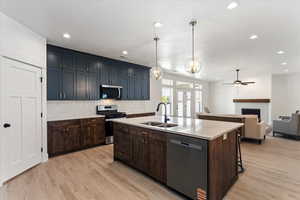 Kitchen with stainless steel appliances, open floor plan, an island with sink, a fireplace, and a chandelier