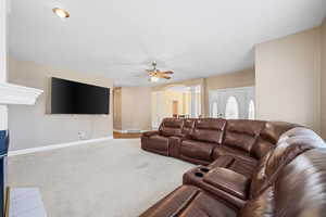 Carpeted living area featuring arched walkways and ceiling fan