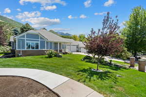 Rear view of house with brick siding, a mountain view, a lawn, a garage, and driveway