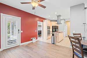 Kitchen featuring island exhaust hood, cream cabinets, a ceiling fan, stainless steel appliances, and plenty of natural light