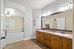 Bathroom with double vanity, light wood-style floors, and ceiling fan