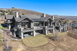 Rear view of property with a patio, a chimney, a lawn, and a mountain view