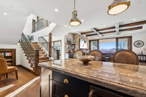 Kitchen featuring light stone countertops, plenty of natural light, dark cabinets, dark wood finished floors, and coffered ceiling