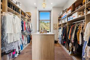 Walk in closet featuring dark wood-style flooring and hanging lights