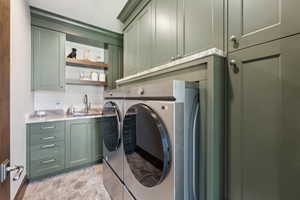 Laundry room with stone finish flooring, washer and clothes dryer, and cabinet space