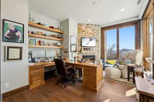 Office area with dark wood-style flooring and built in desk