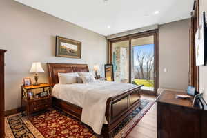 Bedroom with access to outside, wood finished floors, and recessed lighting