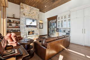 Living room featuring wood finished floors, wooden ceiling, a fireplace, and bar area