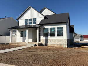 View of front of house featuring a porch, board and batten siding, stone siding, roof with shingles, and a metal roof