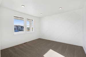 Spare room with baseboards and dark carpet