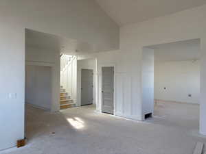 Unfurnished living room with stairs and lofted ceiling