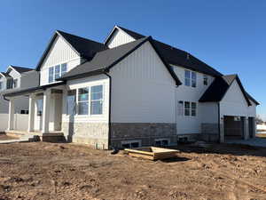 View of front of house with board and batten siding, a porch, an attached garage, and stone siding