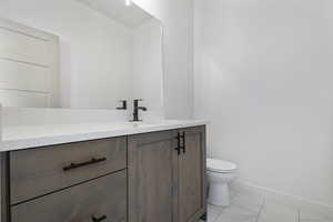 Half bath with vanity and light marble finish flooring