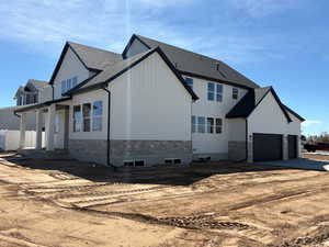 View of side of property with driveway, board and batten siding, stone siding, and an attached garage