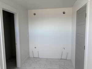 Laundry room with baseboards and light marble finish floors