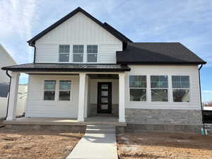 View of front of home featuring board and batten siding, a porch, stone siding, and a metal roof