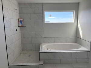 Full bathroom featuring a bath, plenty of natural light, and tiled shower