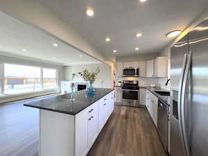 Beautiful Island with breakfast bar, granite counter tops,  featuring stainless steel appliances, dark wood-style floors.