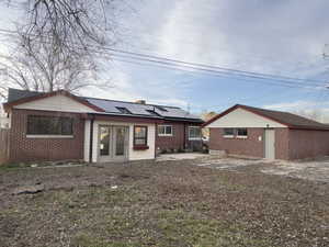Back of the house with SOLAR, brick siding,  and detached garage.